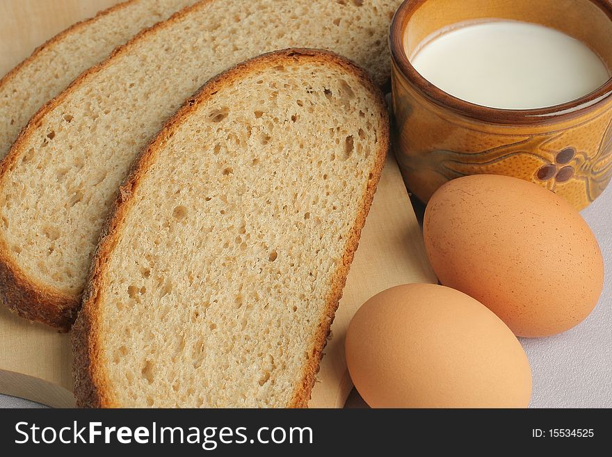 Breakfast close-up. Slices of bread, two brown eggs and cup of milk.