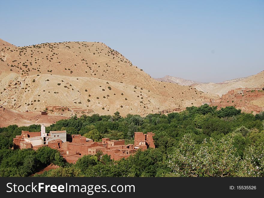 A small berber village is partially concealed by surrounding trees. A small berber village is partially concealed by surrounding trees