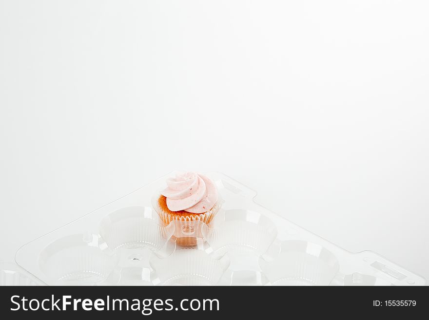 Single remaining strawberry cupcake in plastic container. Single remaining strawberry cupcake in plastic container