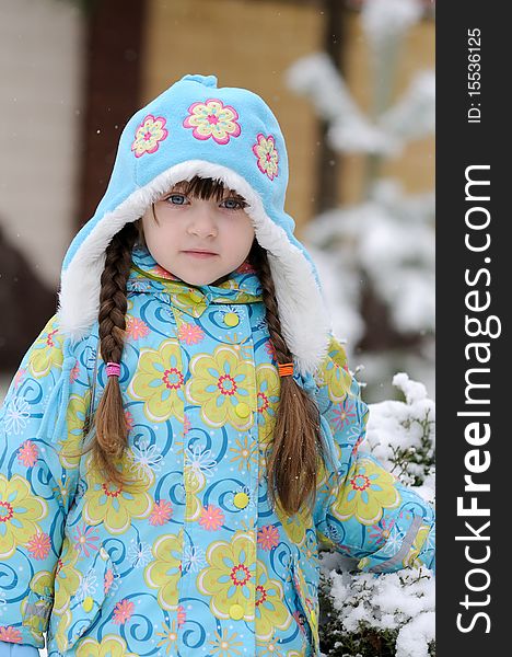 Toddler girl in warm blue hat in winter forest with long plait. Toddler girl in warm blue hat in winter forest with long plait