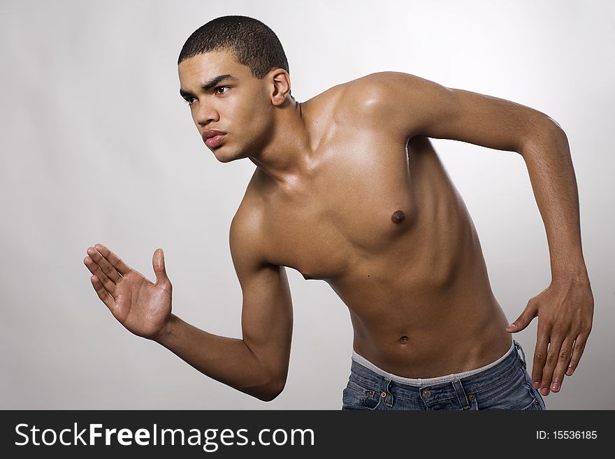 Side view of a muscular young man running in studio