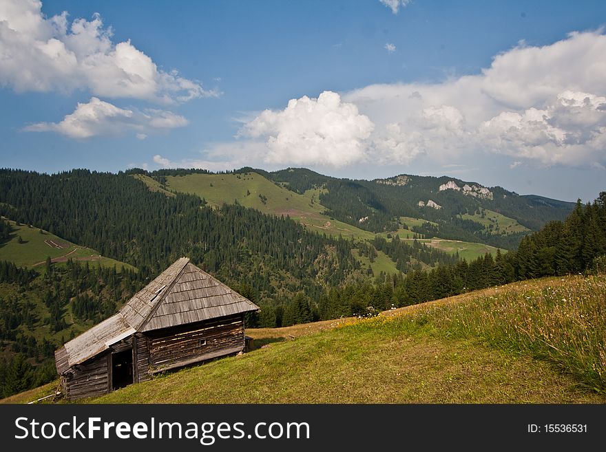 Wooden hut on a meadow, with mountains on background