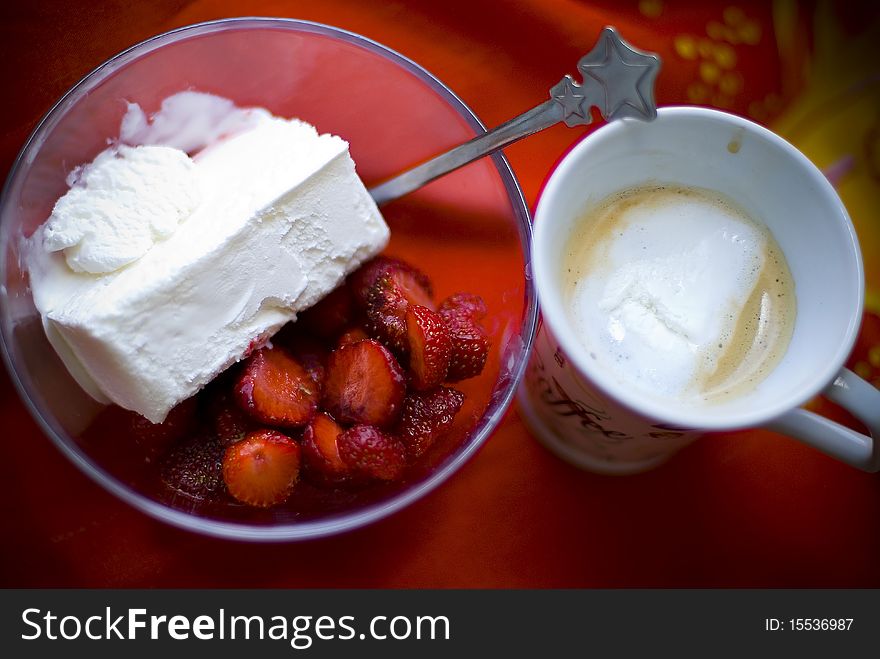 Coffee served with bowl of sliced strawberries and vanilla ice cream . Coffee served with bowl of sliced strawberries and vanilla ice cream