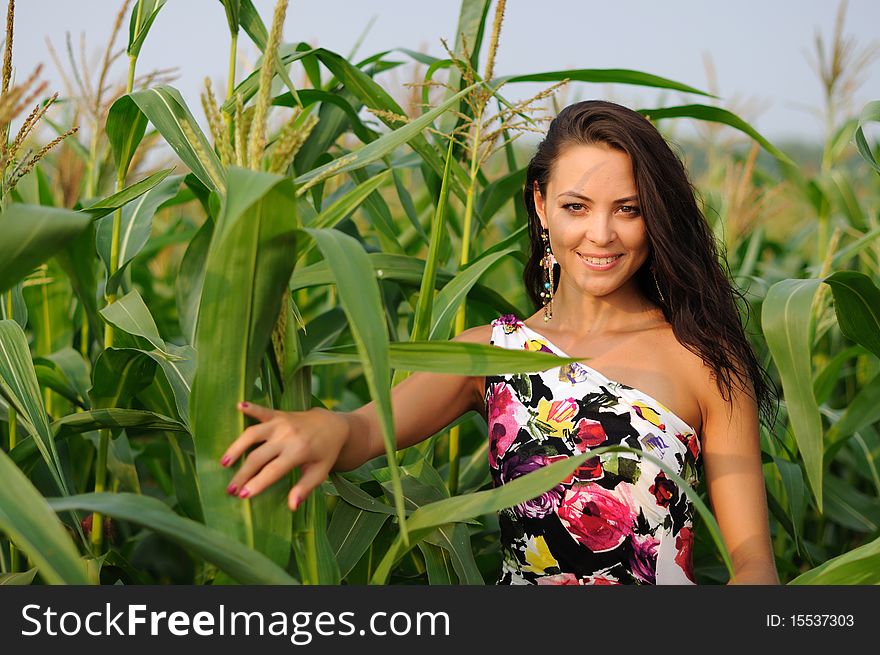 Young girl on a background of green maize and blue sky