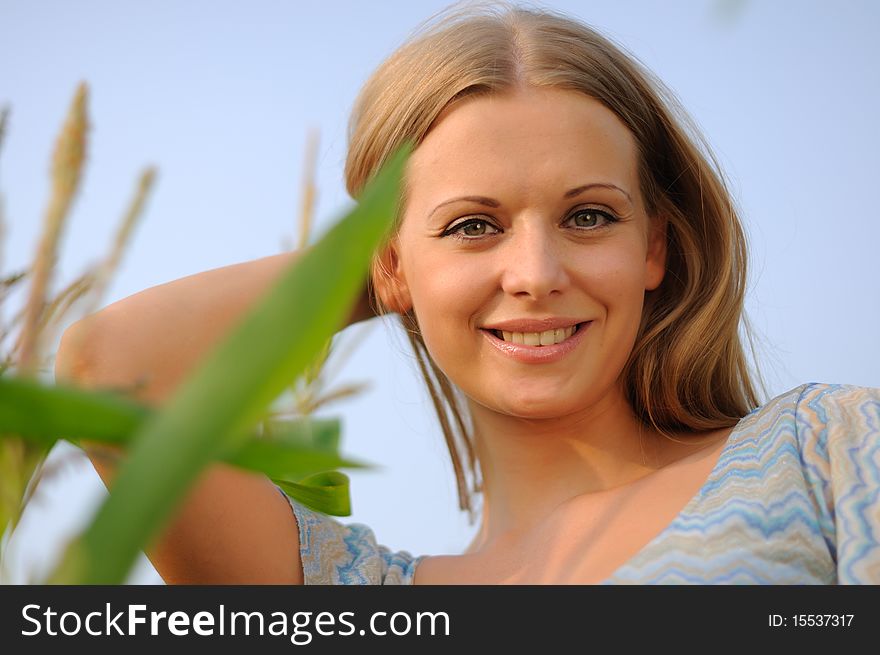 Young girl on a background of green maize and blue sky