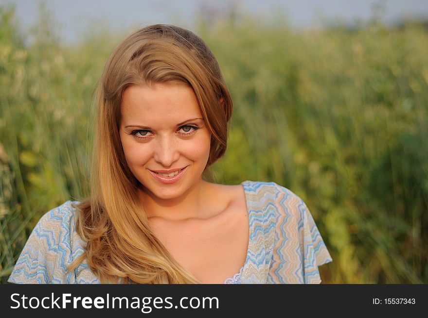 Young girl on a background of green grass and blue sky