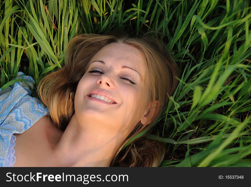 Young girl on a background of green grass and blue sky