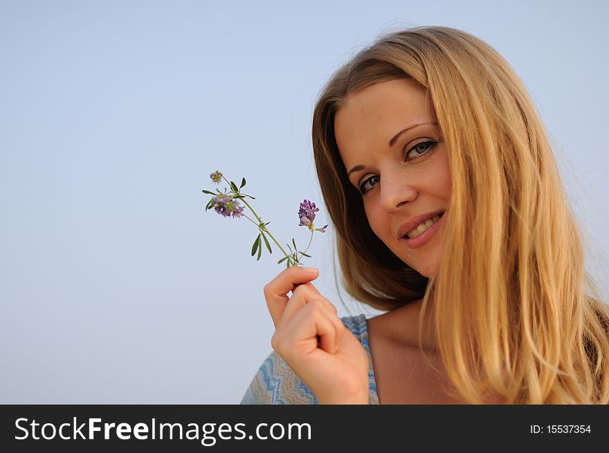 Young girl sitting on green grass against the blue sky