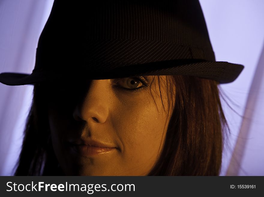 Portrait of a a beautiful young woman with red hair wearing a black pin stripe hat in mysterious strong sidelight. Portrait of a a beautiful young woman with red hair wearing a black pin stripe hat in mysterious strong sidelight