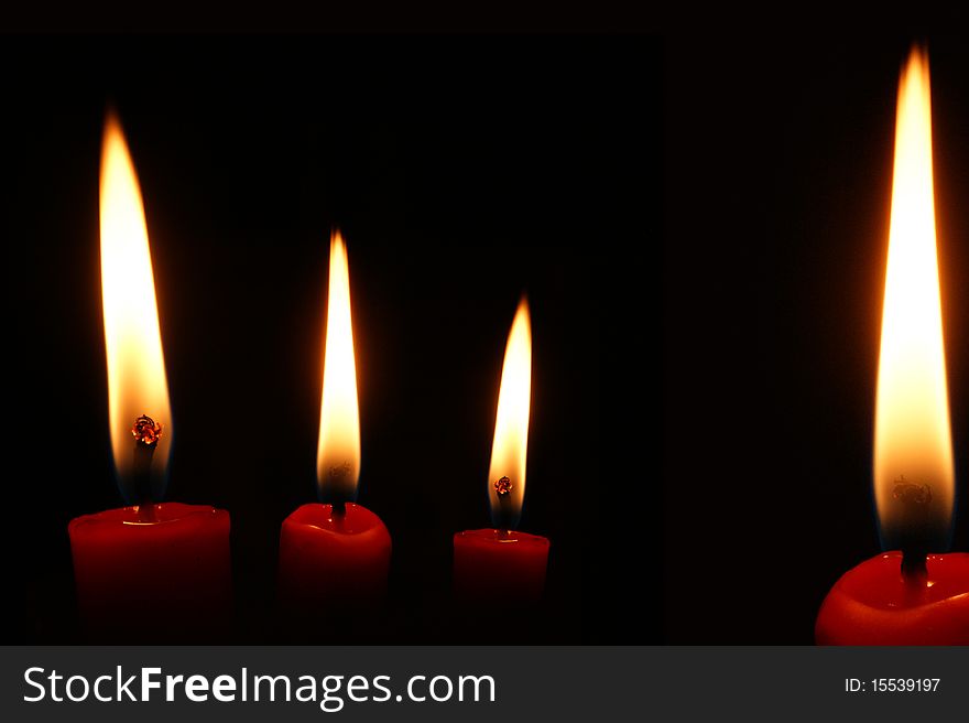 Four red candles on black background