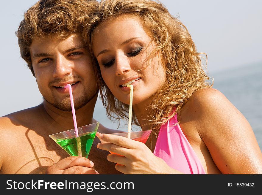 Young Couple On The Seaside With Cocktails