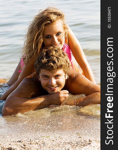 Beautiful young couple having fun on the seaside. Focus on man. Beautiful young couple having fun on the seaside. Focus on man