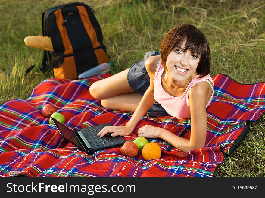 Lovely girl having a rest on picnic with laptop. Lovely girl having a rest on picnic with laptop