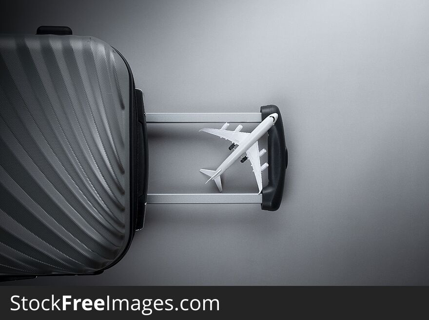 Flat lay grey suitcase with mini airplane on grey background. travel concept - Image