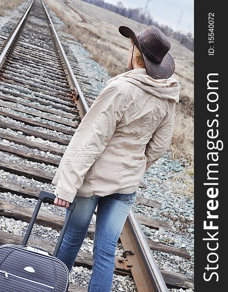 Bag with a long handle, goes on railroad track, on the tourist wearing jeans, stetson and a light raincoat. Bag with a long handle, goes on railroad track, on the tourist wearing jeans, stetson and a light raincoat