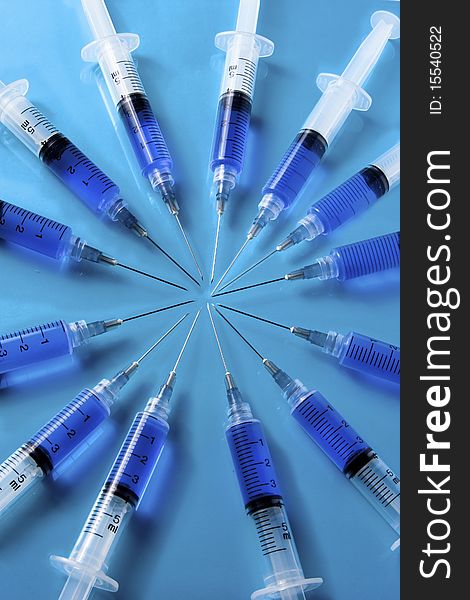 Syringes Forming A Circle On Blue