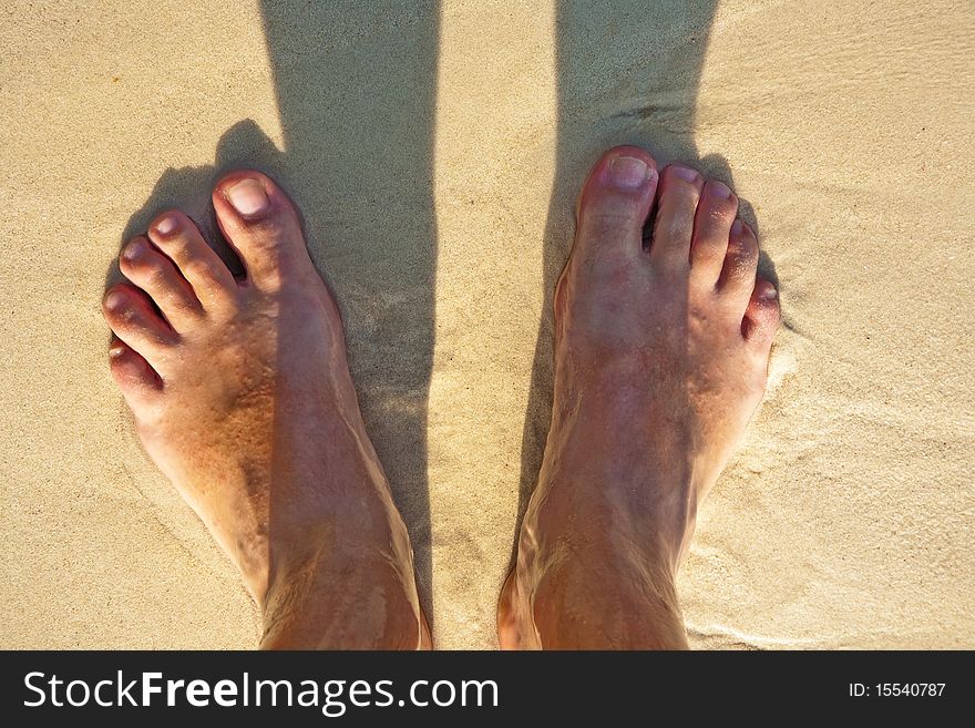 Feet of a man in the fine sand at the beach