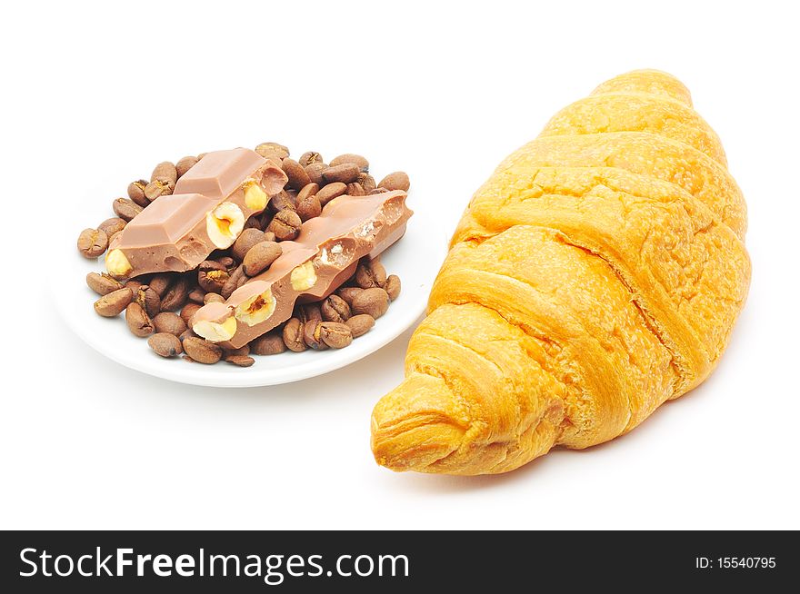 Croissant and a plate with coffe beans and chocolate isolated. Croissant and a plate with coffe beans and chocolate isolated