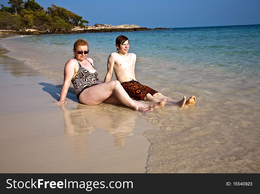 Mother and son sitting at a beautiful sandy beach