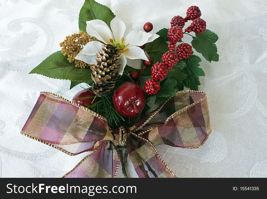 Christmas bouquet with poinsettia, berries, greenery, apples, ribbon on a brocade background