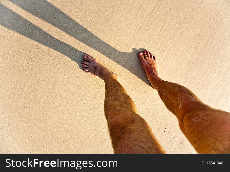 Feet of a man in the fine sand with shadow. Feet of a man in the fine sand with shadow