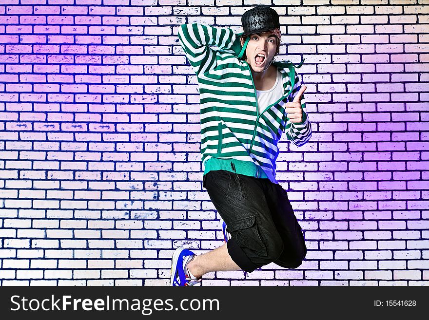 Shot of a jumping over brick background young man.