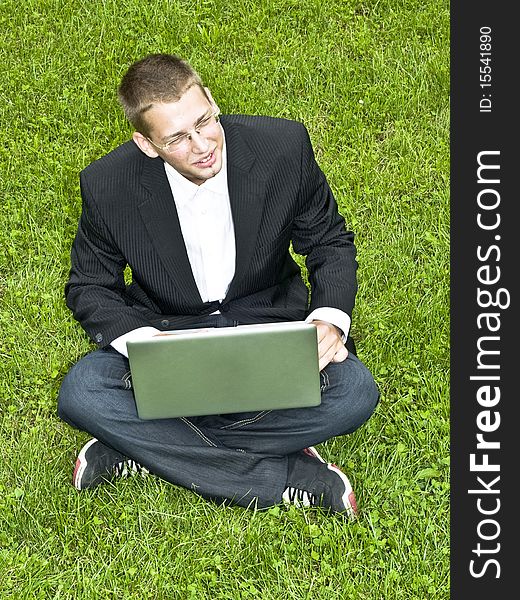 Young businessman on the grass, sitting with his laptop. Young businessman on the grass, sitting with his laptop