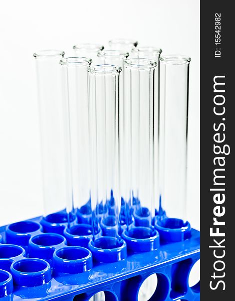 A set of empty glass test tubes in a rack with a white background. A set of empty glass test tubes in a rack with a white background