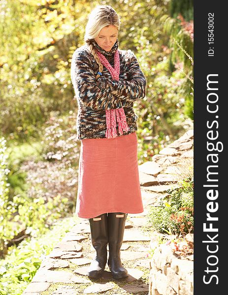 Full Length Portrait Of Young Woman Walking In Autumn Garden