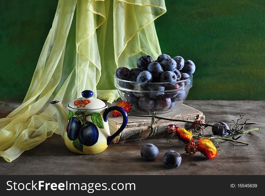 On an old table, lie, plums, tea-pot, book, dry flowers