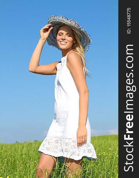 Beautiful blond woman standing outside with a white dress and a sunhat. Beautiful blond woman standing outside with a white dress and a sunhat