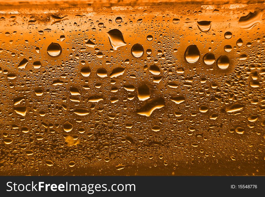 Orange condensation waterdrops on glass with a back light. Orange condensation waterdrops on glass with a back light.