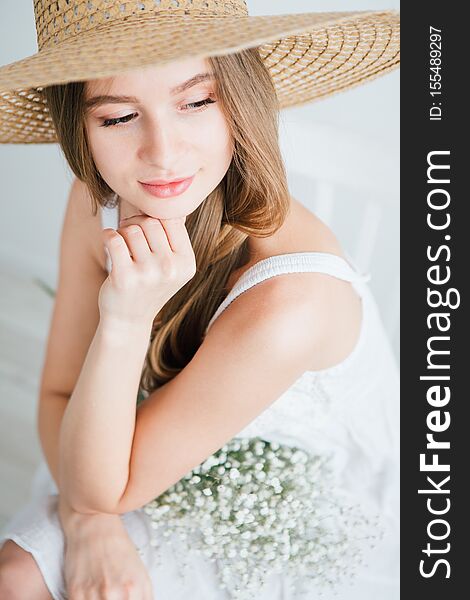 Young beautiful girl with long hair and hat posing with a bouquet of white flowers. Toning