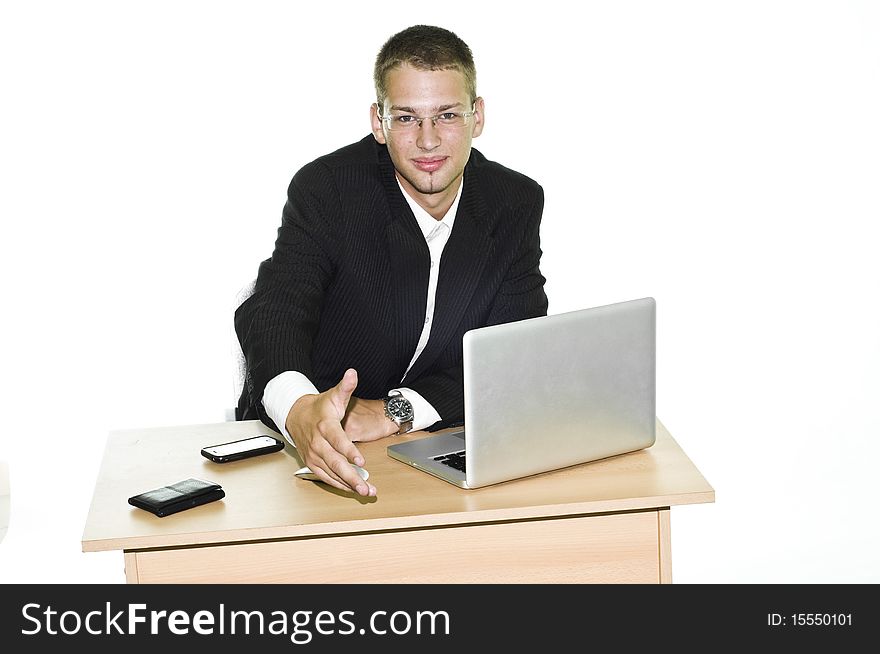 Young businessman holding hand over his desk with laptop, mouse and mobile, isolated on white background