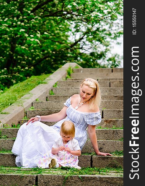 Beautiful woman and her atractive baby daughter sit on a stone steps. Beautiful woman and her atractive baby daughter sit on a stone steps