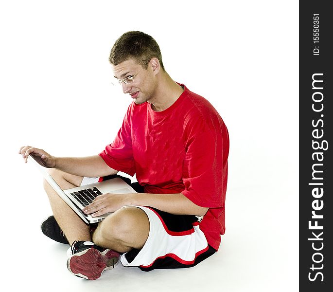 Young man smiling while working on laptop in red shirt, isolated on white background