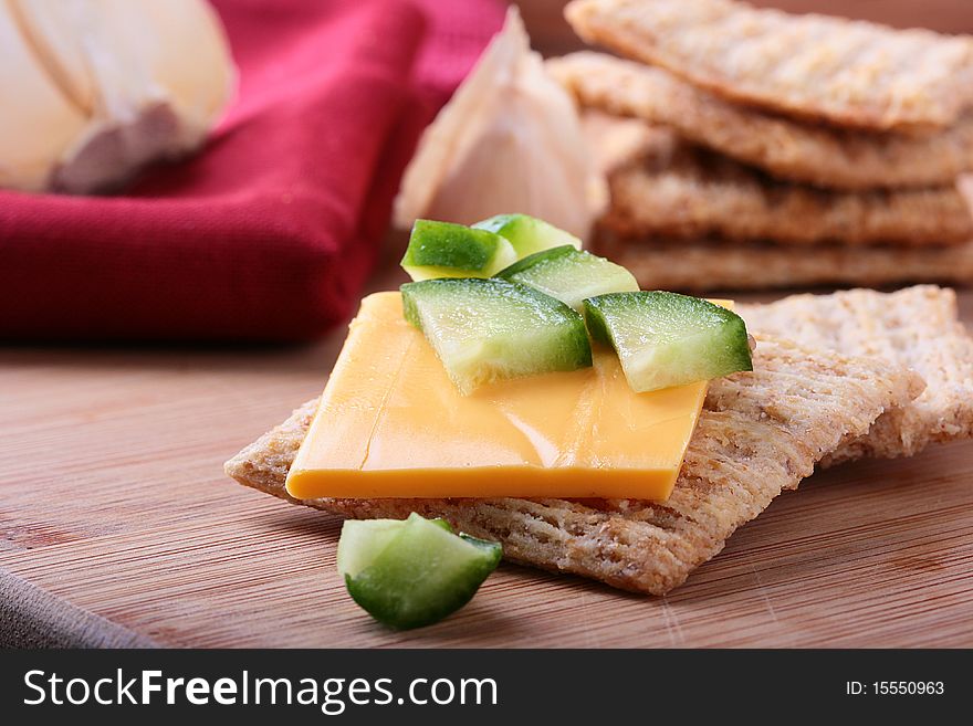 Wheat crackers on a kitchen board with cheese and cucumber.