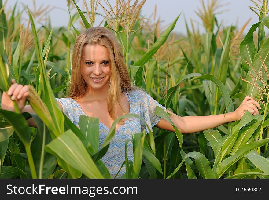 Young girl on a background of green maize and blue sky