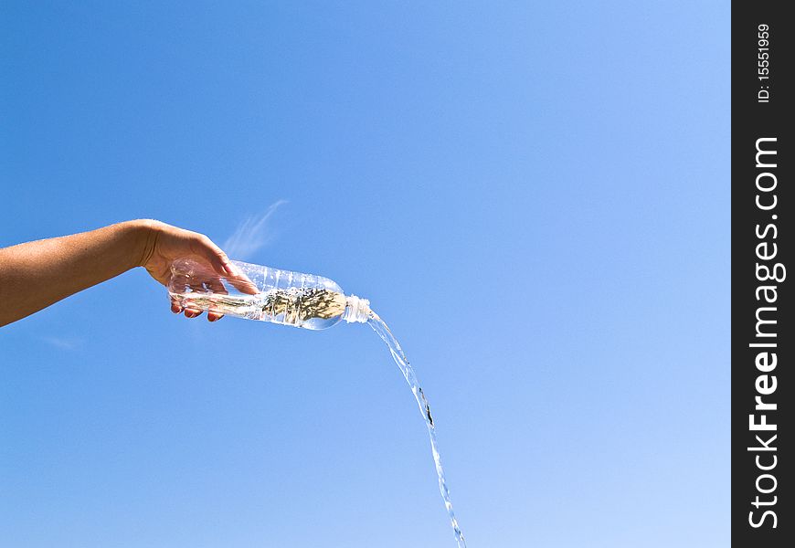 Hand holding bottle of water on the blue sky background