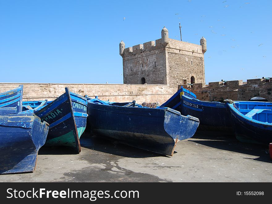 Fishing boats line up along the castle wall at the coastal town of Essaouira in Morocco. Fishing boats line up along the castle wall at the coastal town of Essaouira in Morocco