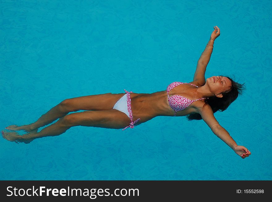 A young girl is relaxing in a swimming pool. A young girl is relaxing in a swimming pool