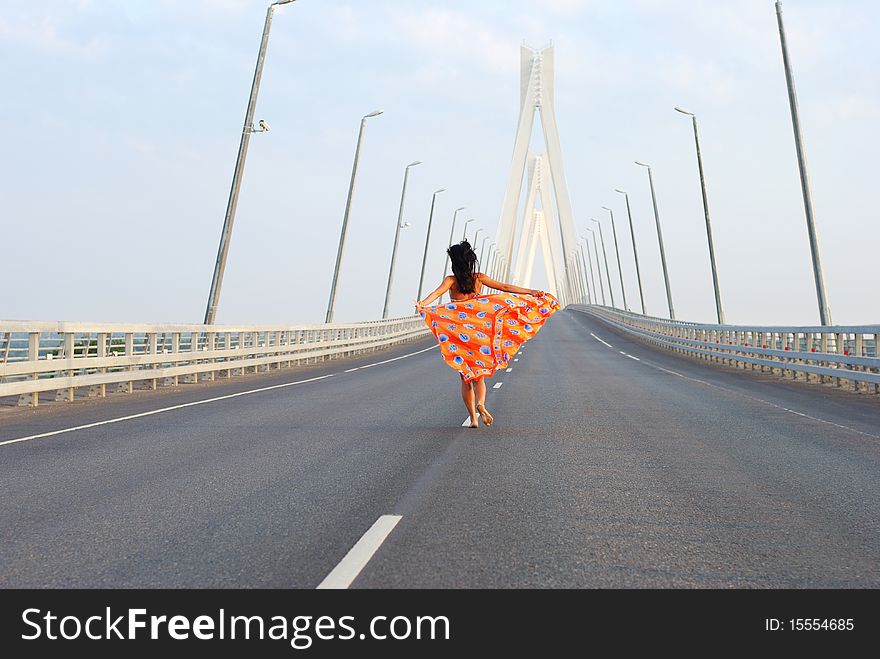 Young adult walking over  bridge with flying red scarf