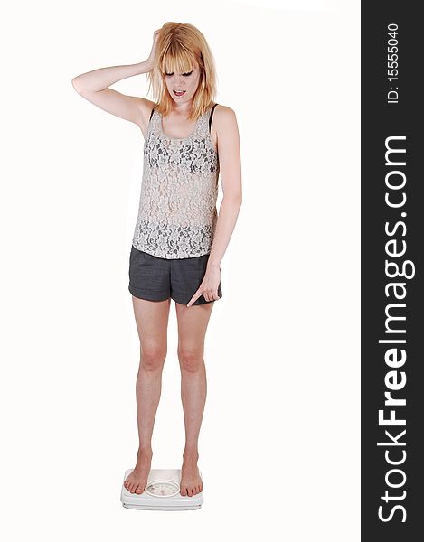 A young woman is very sad, standing on a scale and find out she gains some wait, in shorts and a lace top on white background. A young woman is very sad, standing on a scale and find out she gains some wait, in shorts and a lace top on white background.