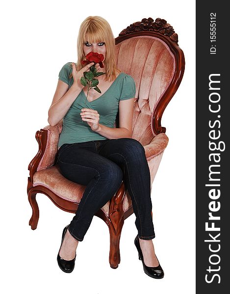 A young pretty woman in jeans and green sweater sitting in an old fashion pink armchair with a rose in her hand, for white background. A young pretty woman in jeans and green sweater sitting in an old fashion pink armchair with a rose in her hand, for white background.