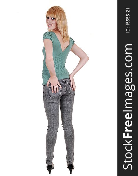 A young pretty and tall woman in jeans and green sweater standing from the back in the studio, holding her butt, over white background. A young pretty and tall woman in jeans and green sweater standing from the back in the studio, holding her butt, over white background.