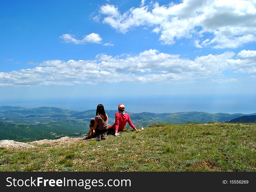A young woman having relax on a green meadow with mountains. A young woman having relax on a green meadow with mountains