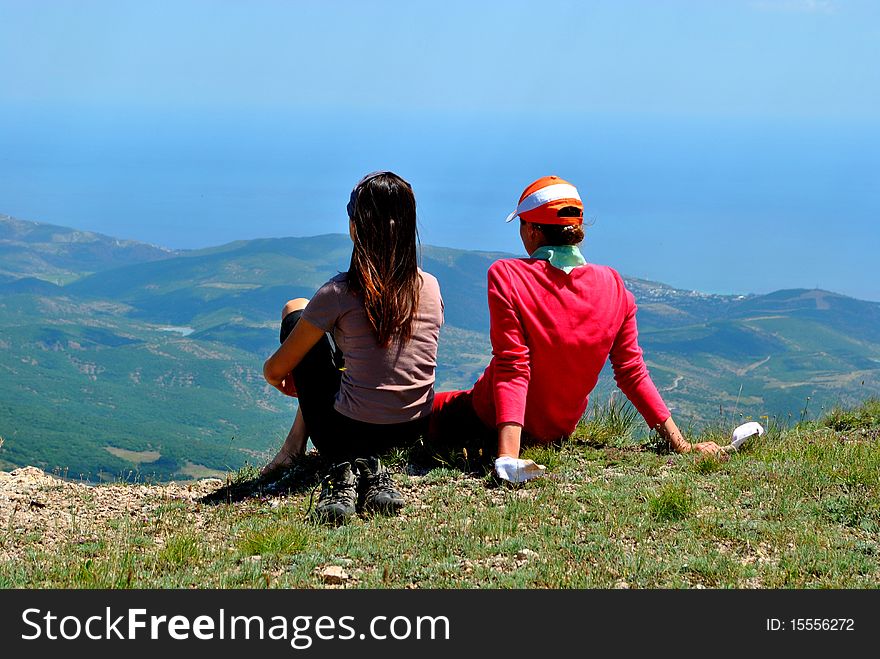 A young woman having relax on a green meadow with mountains