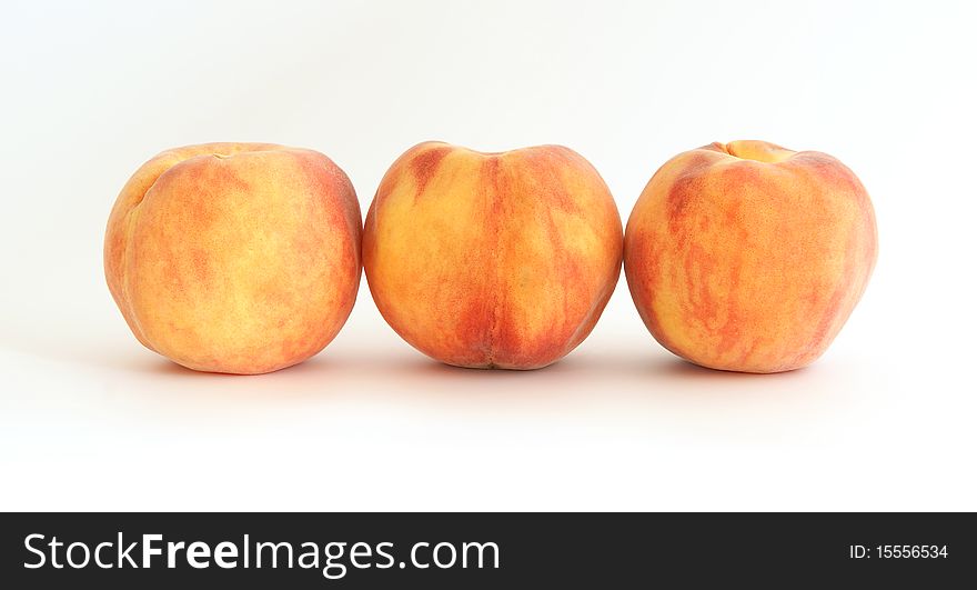 Three large ripe peaches on a white background