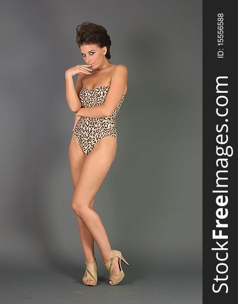 A beautiful woman in a closed leopard swimsuit posing in studio