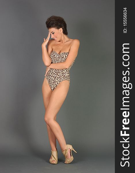 A beautiful woman in a closed leopard swimsuit posing in studio